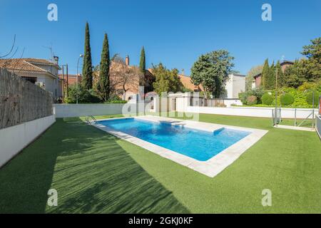 Piscine d'été entourée d'herbe verte avec du marbre blanc, passez une journée ensoleillée Banque D'Images