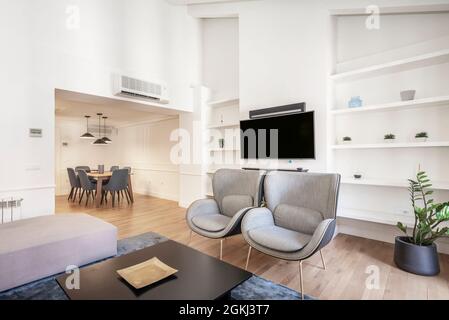 Séjour avec tv et canapés et une table à manger en arrière-plan dans un appartement à Madrid à louer dans airbnb avec murs blancs Banque D'Images