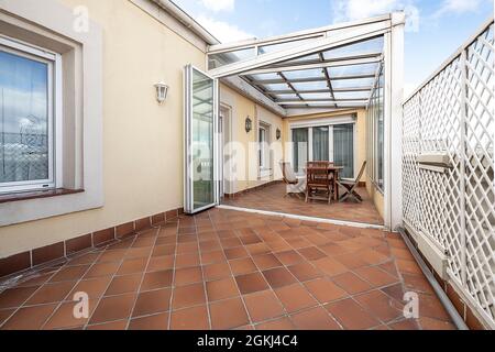 Table à manger et chaises dans une partie de la terrasse couverte d'une grande terrasse urbaine avec ciel bleu Banque D'Images