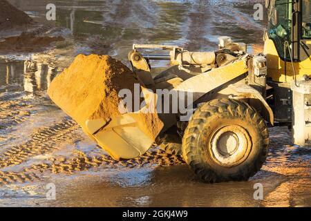 Chargeur sur roues avant du tracteur avec sable dans le godet. Travaux de terrassement au concept de chantier. Banque D'Images