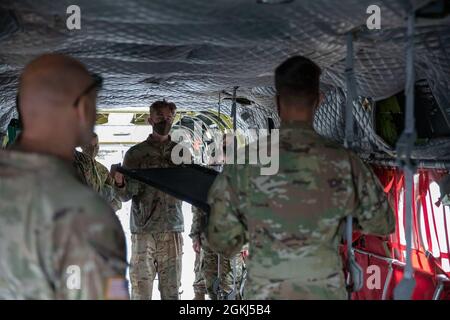 Sergent de l'armée Kevin Swanson, ingénieur de vol de la Compagnie B, 2e Bataillon de l'aviation générale de soutien, 501e Régiment de l'aviation, Brigade de l'aviation de combat, 1re Division blindée de fort Bliss, Texas, montre des soldats de la 738e compagnie médicale de soutien de zone, 81e Commandement de la troupe, Garde nationale de Lafayette de l'Indiana, Ind., Comment apposer une litière dans un avion CH-47 Chinook, pendant l'exercice Guardian Response 21 à Camp Atterbury, Ind., le 29 avril 2021. L'intervention du tuteur est un exercice d'intervention d'urgence en territoire intérieur à plusieurs composantes dirigé par la 78e Division d'entraînement de la Réserve de l'Armée de terre. Banque D'Images