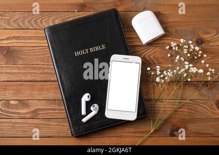 Sainte Bible, écouteurs, téléphone portable et fleurs de sophila sur fond de bois Banque D'Images