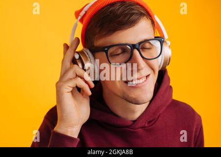 gros plan portrait d'un jeune homme avec un casque sur sa tête, musique dans de grands écouteurs, yeux fermés utilise le fantasme pour écouter de la musique Banque D'Images