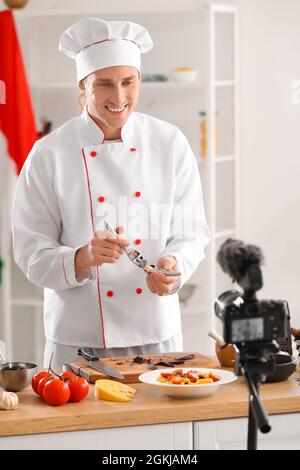 Beau chef avec presse à ail enregistrement vidéo dans la cuisine Banque D'Images