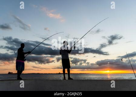 Salvador, Bahia, Brésil - 23 mai 2021 : silhouette de pêcheurs avec leurs poteaux au coucher du soleil. Banque D'Images