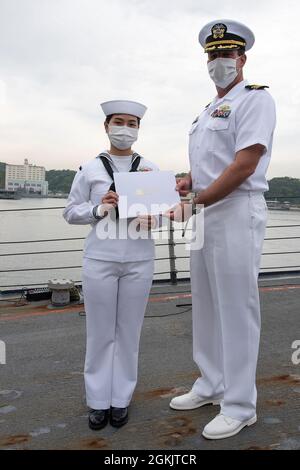 YOKOSUKA, Japon (7 mai 2021) — Spécialiste des services de détail, 3e classe Fangfang Wen, originaire de Chine, pose avec son certificat de citoyenneté à côté de Cmdr. Robert Briggs, commandant de l'USS Mustin (DDG 89) lors d'une cérémonie de naturalisation des services de citoyenneté et d'immigration des États-Unis. L'événement a été la première cérémonie de naturalisation tenue à bord d'un navire actif de la Marine américaine pendant la pandémie COVID-19. Mustin est déployé au Japon et est stationné au Commandant Fleet Activities Yokosuka (CFAY) dans le cadre de la 7e flotte des États-Unis. Depuis plus de 75 ans, CFAY fournit, maintient, Banque D'Images