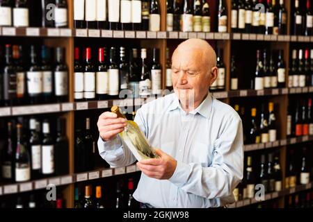 le pensionné choisit le vin blanc dans un magasin de spiritueux Banque D'Images