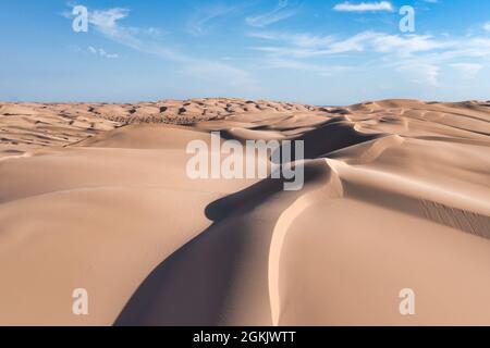 Grandes dunes de sable avec texture, motifs, lumière et ombre. Ciel bleu avec nuages blancs Banque D'Images