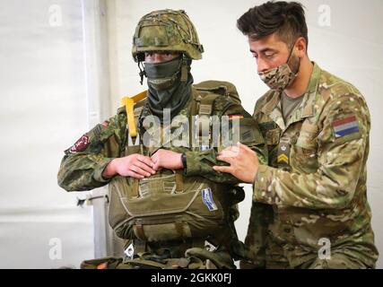 Un soldat néerlandais affecté au 11e Bataillon aéroporté aide un soldat allemand affecté au 31e Régiment parachutiste de la 1re Brigade aéroportée à mettre son équipement sous tension lors de la réponse Swift 21 à Boboc, en Roumanie, le 10 mai 2021. SWIFT Response 21 est un exercice lié au Defender 21, un exercice annuel à grande échelle mené par l'armée américaine et mené conjointement par l'armée de terre, un exercice multinational conçu pour renforcer la préparation et l'interopérabilité entre les forces armées américaines, de l'OTAN et des partenaires. Banque D'Images