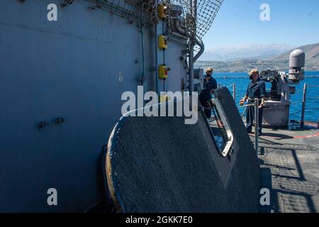 210513-N-RG587-1013 SOUDA BAY (GRÈCE) (le 13 mai 2021) le Matelot de 1re classe de Gunner, Peter Dicandia, de long Island, New York, à gauche, abaisse une trappe de chargement de torpille alors que le croiseur à missiles guidés de classe Ticonderoga USS Vella Gulf (CG 72) quitte Souda Bay, Grèce, le 13 mai 2021. Le golfe de Vella fait une visite régulière du port de Souda Bay pour se ravitailler et recevoir des fournitures. Banque D'Images