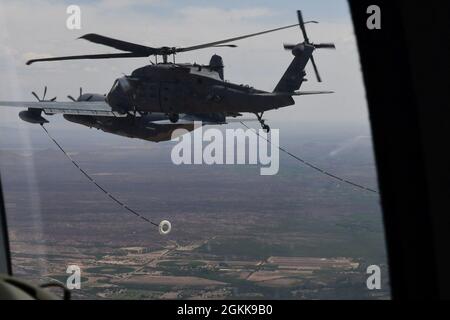 Une US Air Force HH-60W Jolly Green II affectée au 41e Escadron de sauvetage, à la base aérienne Moody, en Géorgie, termine un ravitaillement en vol avec un HC-130J combat King II affecté au 79e Escadron de sauvetage, à la base aérienne Davis-Monthan, en Arizona, le 13 mai 2021. L'hélicoptère HH-60W a pour mission de mener des opérations de recherche et de sauvetage de combat de jour ou de nuit pour récupérer du personnel isolé, des opérations de recherche et de sauvetage civils, des évacuations médicales, des interventions en cas de catastrophe, de l'aide humanitaire, de la coopération en matière de sécurité et des conseils en matière d'aviation, Le soutien de vol spatial de la NASA, ainsi que le commandement et le contrôle des opérations de sauvetage. Banque D'Images