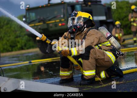 Les pompiers de la 142e Escadre du guar de l'Oregon Air National effectuent un exercice de tir en direct avec les pompiers du corps des Marines à la base du corps des Marines, à Hawaï, le 14 mai 2021. Ce brûlage fait partie d'un exercice conjoint à plus grande échelle qui comprend la familiarisation des avions, la formation à la sortie, ainsi que la co-formation et le mentorat des pompiers moins expérimentés. Banque D'Images