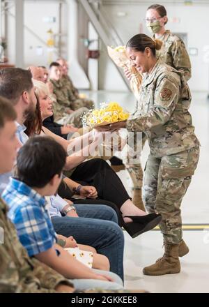 Tech. Sgt. Alicia Williams, recruteuse auprès de la Garde nationale aérienne du Kentucky, présente un bouquet de roses à l'épouse du Sgt principal. James Tongate, le nouveau chef du commandement de l'État, lors de sa cérémonie d'accession à la responsabilité à la base de la Garde nationale aérienne du Kentucky à Louisville, Ky., le 15 mai 2021. Banque D'Images