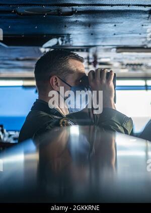 210519-N-IG124-1085 OCÉAN ATLANTIQUE (19 mai 2021) Cmdr. Tanner Acker, de Bessemer, Alabama, utilise une paire de jumelles pour surveiller les drapeaux de signalisation lors d'un réapprovisionnement en mer avec le lubrificateur USNS Joshua Humphreys (T-AO 188) sur le pont du porte-avions de classe Nimitz Harry S. Truman (CVN 75) pendant les essais en mer après avoir complété une disponibilité incrémentielle de transporteur étendu. Les essais en mer comprennent un essai complet des systèmes et des technologies du navire afin de s’assurer que le navire est prêt à reprendre ses activités. Banque D'Images