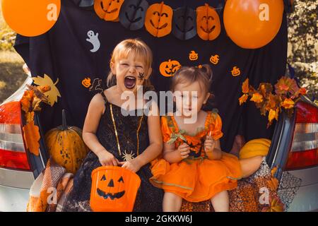 Enfants célébrant Halloween dans le coffre de la voiture. Amis enfants filles se préparant pour les vacances d'octobre en plein air. Trick ou tronc Banque D'Images