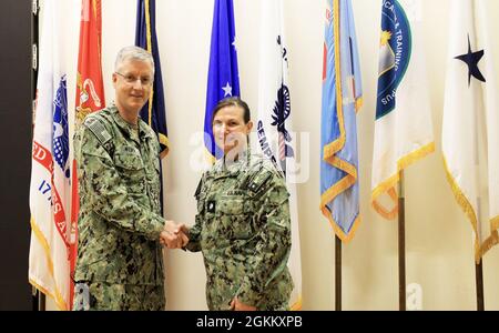 Cmdr. Pamela Klepac-Tulensru, directrice du commandement de soutien des forces médicales de la Marine pour l'administration, accepte une pièce au nom du lieutenant Biagio Mezzasalma de la Rear ADM. Tim Weber, commandant des Forces médicales navales du Pacifique et directeur du corps des services médicaux de la Marine, mai 19. Weber, qui a rencontré des officiers du SMC de la Marine lors de sa visite à San Antonio, a remis la pièce à Mezzasalma pour son travail de coordination de la distribution du vaccin COVID-19 pour le personnel de la Marine à travers la base conjointe de San Antonio. Banque D'Images