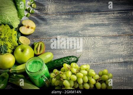 Pot en verre mugs avec smoothie vert santé, lime, pomme, kiwi, raisin, avocat, laitue sur fond de bois. Concept alimentaire végétalien. Espace pour le texte Banque D'Images