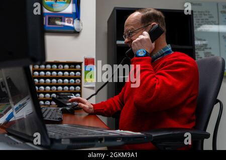 Denny Hostetter, spécialiste de l'engagement communautaire du bureau des affaires publiques de l'escadre de la base aérienne 673d, répond au téléphone à la base conjointe Elmendorf-Richardson, Alaska, le 24 mai 2021. L'engagement communautaire est responsable de l'exécution de programmes actifs de relations communautaires afin d'améliorer le moral, la confiance du public et le soutien. Banque D'Images