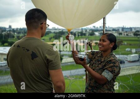 Caporal du corps des Marines des États-Unis Alicia Lucio, prévisionniste météorologique et océanographique (METOC) de l’Escadron de contrôle aérien maritime (MACS-4), à droite, et Cpl. Peter Chang, un Forecaster METOC du 3e Bataillon du renseignement, prépare un ballon météorologique pour un vol lors d'un événement d'entraînement à la base aérienne de Kadena, Okinawa (Japon), le 25 mai 2021. La 1re Escadre des aéronefs maritimes améliore les capacités pour s'assurer que, lorsque nos partenaires et nos alliés ont besoin de nous, nous continuerons à être en mesure de répondre à l'appel, comme nous l'avons fait par le passé. Banque D'Images