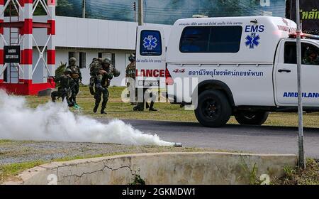 LOPPBURI, Thaïlande – Un Béret vert avec 2e Bataillon, 1er Groupe des forces spéciales (Airborne) conseille les soldats avec l'Armée Royale de Thaïlande comme ils ont théoriquement évacuer une victime pendant le cours de base des Forces spéciales de l'Armée Royale de Thaïlande (RTA) à Loppburi, Thaïlande, avril 2021. Le cours de base des forces spéciales RTA comprend 15 semaines d'entraînement qui couvre les tactiques des petites unités, l'entraînement aéroporté et l'entraînement de survie, suivi d'un exercice culminant englobant le cours. Banque D'Images