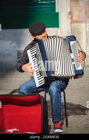 Rome, Italie - 01 janvier 2013 : un musicien de rue joue de l'accordéon près de Santa Cecilia dans l'église Trastevere pour des conseils et aussi pour promouvoir sa chanson sur CD. Banque D'Images