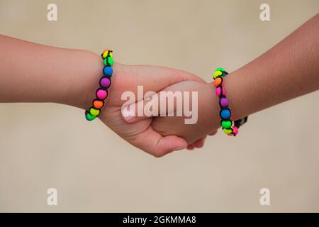 Les enfants tiennent les mains, bracelets colorés. Concept d'amitié. Banque D'Images