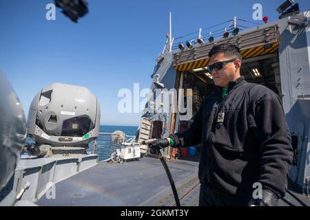 OCÉAN ATLANTIQUE (30 mai 2021) le technicien en aviation de 2e classe Soo Lee pulvérise de l'eau sur un hélicoptère MH-60R Seahawk, attaché à l'Escadron de frappe maritime (HSM) 79, à bord du destroyer de missile guidé de classe Arleigh Burke USS Roosevelt (DDG 80), le 30 mai 2021. Roosevelt participe à AT-Sea Demo/formidable Shield, mené par les forces navales de frappe et de soutien OTAN pour le compte de la Sixième flotte des États-Unis, est un exercice de défense aérienne et antimissile (IAMD) intégrée en direct qui améliore l'interopérabilité des alliés à l'aide des structures de rapport de commandement et de contrôle de l'OTAN. Banque D'Images