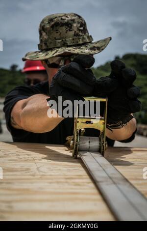 U.S. Navy GSM1 Justin Yates, mécanicien de systèmes à turbine à gaz de Naval Beach Unit (NBU) 7, fixe les palettes à un coussin d'air d'embarcation d'atterrissage (LCAC) avec des sangles sur la base navale de White Beach, Okinawa, Japon, le 1er juin 2021. Marines de mlg 3d et marins de la NBU-7 intégrés pour charger et transporter du personnel et de l’équipement à l’appui de la tour de surveillance de l’exercice Poseidon. La NBU-7 est une unité opérationnelle déployée à l'avant qui contribue directement aux capacités de base de la Maritime Sea Power des États-Unis en facilitant le mouvement des troupes, de l'équipement, des véhicules et des fournitures provenant du transport maritime amphibie à travers la plage. 3 Banque D'Images