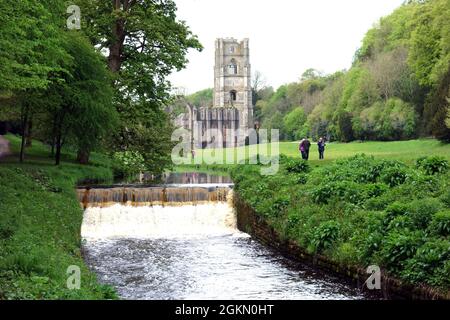 Les gens qui marchent à côté de Gray marchent sur la rivière Skell à l'abbaye de Fountains près de Ripon dans le North Yorkshire, Angleterre, Royaume-Uni. Banque D'Images