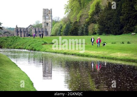 Les gens qui marchent à côté de Gray marchent sur la rivière Skell à l'abbaye de Fountains près de Ripon dans le North Yorkshire, Angleterre, Royaume-Uni. Banque D'Images
