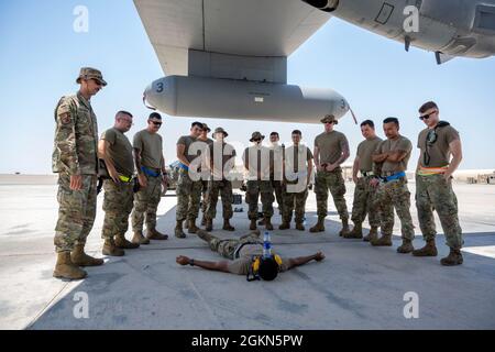 Les aviateurs de la US Air Force du 380e Escadron de maintenance d'aéronefs expéditionnaires, base aérienne Al Dhafra, Émirats arabes Unis, profitent de quelques minutes à l'ombre d'une aile EC-130H Compass Call avant son lancement le 2 juin 2021. Les membres qui soutiennent actuellement la mission Compass Call de l'ADAB sont déployés en tant qu'équipe de la base aérienne de Davis-Monthan, à Tucson, en Arizona, ce qui signifie qu'ils travaillent le même horaire pendant la durée de leur déploiement, ce qui favorise le moral et la camaraderie, et optimise l'efficacité de l'équipe. Banque D'Images