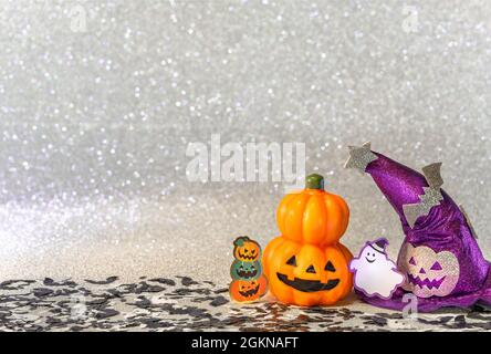 Photographie de concept représentant une tête de citrouille jack o lanterne d'halloween et un chapeau de sorcières pourpre avec un fantôme drôle souriant et des chauves-souris découpées en carton aga Banque D'Images