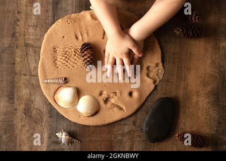 Les enfants jouent avec de la pâte à sel sur la table de cuisine. Les mains moulez l'argile avec leurs propres mains pour créer des jouets faits maison sans taille. Cours créatif avec une te Banque D'Images