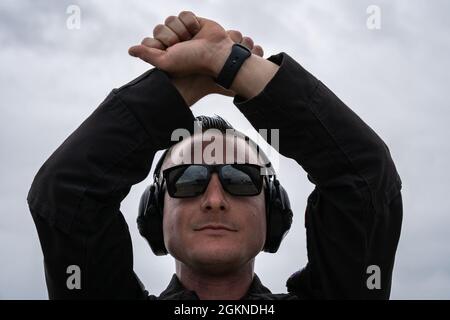 Le sergent technique Lenny Buscemi de la Force aérienne des États-Unis, le chef d'équipage de l'équipe de démonstration F-22 Raptor, donne le signal de la main de marshalling “pause” lors du stationnement d'un F-22 Raptor après une démonstration au salon de l'aviation de Chennault, le 4 juin 2021, à Lake Charles, en Louisiane. L'équipe de démonstration F-22 utilise de nombreux signaux manuels pour communiquer entre le pilote lors du lancement et de la récupération de l'avion. Banque D'Images