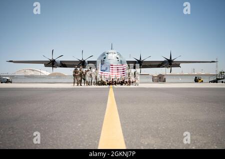 Les membres du 75e Escadron de transport aérien expéditionnaire arboraient un drapeau américain devant un avion C-130J Super Hercules avant de mener une mission de transport aérien de combat, le 6 juin 2021. Le 75e SAE soutient la Force opérationnelle conjointe combinée - Corne de l'Afrique (CJTF-HOA) avec des évacuations médicales, des secours en cas de catastrophe, des opérations humanitaires et des opérations de chute d'air. Banque D'Images