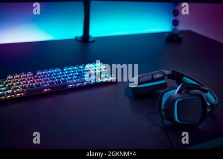 Accessoires de jeu sur table sombre. Clavier avec rétroéclairage couleur et casque stéréo. Jeux informatiques professionnels, esport d'affaires et en ligne WO Banque D'Images