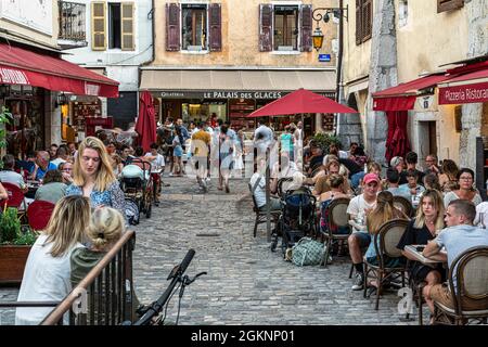 Les touristes se baladent dans les rues anciennes de la vieille ville d'Annecy. Les bars à souvenirs et les cafés en plein air attirent les touristes. Annecy, France Banque D'Images