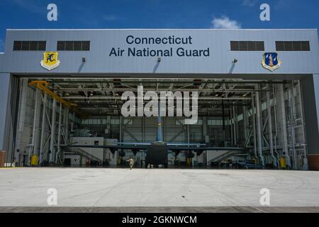 Des aviateurs du 103e Groupe de maintenance remorquent un avion Hercules C-130H dans la cellule à combustible et le hangar de contrôle de la corrosion à la base de la Garde nationale aérienne Bradley, East Granby (Connecticut), le 8 juin 2021. L’installation permet aux agents d’entretien d’effectuer des tâches d’entretien des systèmes d’alimentation en carburant et des lavages d’aéronefs, qui sont essentiels au maintien de l’état de préparation de la flotte C-130H Hercules de la 103e Escadre de transport aérien. Banque D'Images