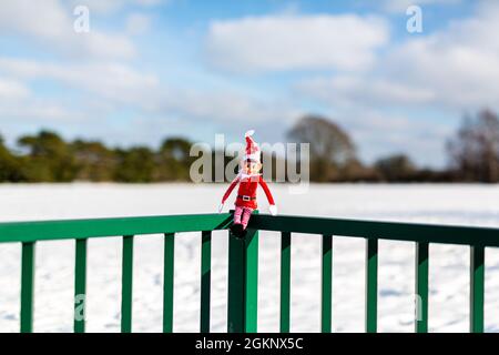 Un lutin de Noël nain assis à l'extérieur dans le paysage d'hiver enneigé en profitant du soleil d'hiver. Elfe sur l'étagère, naughty, noël, espiègle Banque D'Images