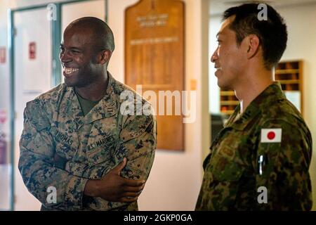 Le capitaine du corps des Marines des États-Unis, Dominique Thomas, à gauche, commandant de la compagnie d'armes, 1er Bataillon, 7e Régiment des Marines avec la force de rotation marine - Darwin, rit avec un membre de la force d'autodéfense terrestre du Japon lors d'un thé matinal à Robertson Barracks, Darwin, NT, Australie, le 9 juin, 2021. Des membres de la Force de défense australienne, du MRF-D et du JGDSF ont assisté à l'événement pour se familiariser avec l'exercice trilatéral à venir, le sud de Jackaroo. Les liens de défense entre les États-Unis, leurs alliés et les pays partenaires sont essentiels à la sécurité et à la coopération régionales. Banque D'Images