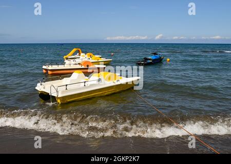 Trois pédalos et un jet ski ancré sur le bord de mer de la côte toscane dans une journée ensoleillée d'été, Marina di Castagneto Carducci, Livourne, Toscane Banque D'Images