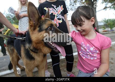 DNIPRO, UKRAINE - 14 SEPTEMBRE 2021 - Un élève peint en visage de l'orphelinat Barvinok attaque un chien de service nommé Jack lors de l'événement caritatif ukrainien Dumpling Holiday organisé par l'équipe de la Fondation de bienfaisance de Real Dreams, Dnipro, Ukraine orientale Banque D'Images