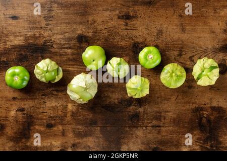 Tomatillos, tomates vertes, prises d'en haut avec espace de copie. Ingrédients de cuisine mexicaine sur fond de bois rustique sombre Banque D'Images