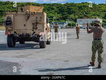 WHITE BEACH, Japon (juin 10, 2021) Naval Beach Unit 7 guide du personnel a III Marine Expeditionary Force véhicules tactiques légers conjoints pour l’embarquer sur un utilitaire d’atterrissage au commandant, activités de la flotte installation navale de White Beach d’Okinawa, au Japon le 10 juin 2021. Le navire d'assaut amphibie de classe américaine USS America (LHA 6) est amarré côté jetée en arrière-plan. Banque D'Images