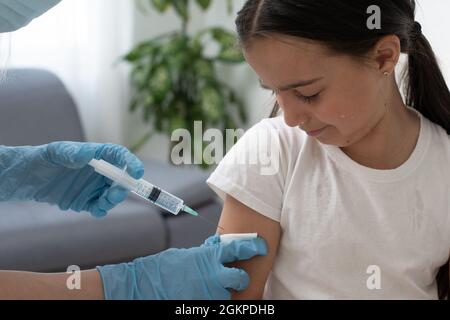 Une petite fille avec des larmes dans les yeux a très peur de la vaccination. Le bébé pleure la douleur en fermant les yeux. Portrait d'un enfant qui l'est Banque D'Images