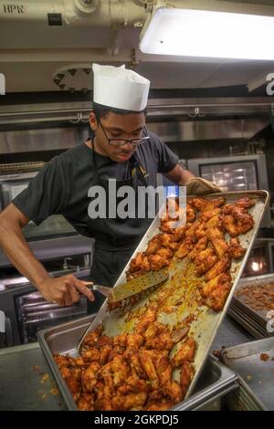 Spécialiste culinaire le Matelot de 1re classe Laquouan Jefferson, de Baltimore, affecté au département d'approvisionnement de l'USS Gerald R. Ford (CVN 78), prépare des aliments dans la galerie arrière de Ford, le 12 juin 2021. Ford est en cours dans l'océan Atlantique en menant des essais de choc en pleine mer (FSST). La Marine américaine effectue des essais de choc sur de nouveaux modèles de navires à l'aide d'explosifs vivants pour confirmer que nos navires de guerre peuvent continuer à répondre aux exigences de mission exigeantes dans les conditions difficiles qu'ils pourraient rencontrer au combat. Banque D'Images