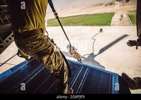 Soldats des forces spéciales de l'armée américaine affectés au 19e Groupe des forces spéciales (Airborne), Garde nationale de l'armée de l'Utah, parachutistes de l'armée royale marocaine, Et les commandants de la Marine royale marocaine conduisent un entraînement rapide de corde à partir d'un Chinook MH-47 du 160e Régiment d'aviation d'opérations spéciales lors de l'exercice African Lion 2021 à Tifnit Maroc, Afrique, le 14 juin 2021. African Lion 2021 est l'exercice annuel le plus important, conjoint et le plus important du Commandement de l'Afrique des États-Unis, organisé par le Maroc, la Tunisie et le Sénégal, le 7-18 juin. Plus de 7,000 participants de neuf nations et de l'OTAN s'entraînent ensemble en mettant l'accent sur l'amélioration de la réadmission Banque D'Images