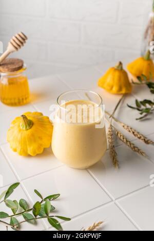 smoothie naturel à base de citrouille jaune. boisson d'automne au miel et au lait. sur fond clair, position verticale Banque D'Images