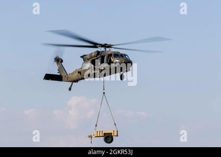 Les soldats de l'air de la Marne affectés au 603e Bataillon de soutien de l'aviation, 3e Brigade de l'aviation de combat, 3e Division d'infanterie, utilisent un hélicoptère UH-60 Black Hawk pour soulever une remorque pendant les opérations de chargement de harnais à l'aérodrome de l'Armée Hunter, juin 17. Les soldats ont mené la formation de chargement de harnais afin de se familiariser avec les opérations et de transporter avec succès les capacités logistiques par voie aérienne. Banque D'Images