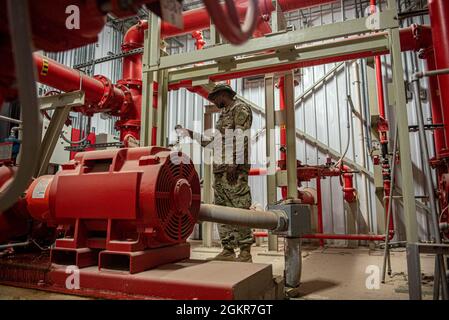 Airman 1re classe Brandon Johnson, 379e Escadron de génie civil expéditionnaire, entretien des systèmes d'eau et de carburant, vérifie le manomètre d'un réservoir de stockage d'eau le 16 juin 2021 à la base aérienne Al Udeid, au Qatar. Le contrôle du manomètre permet de s'assurer que le système de distribution fournit une pression adéquate au client le plus éloigné du système et qu'il est toujours capable de répondre aux besoins de la mission. Banque D'Images